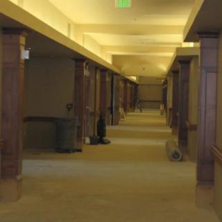 A long, indoor hallway with wooden columns and warm lighting.