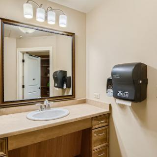 A well-lit bathroom featuring a stylish vanity, mirror, and hand dryer.