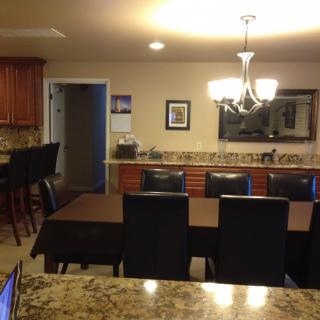 A cozy kitchen and dining area featuring a large table with chairs, a chandelier, and wooden cabinetry.