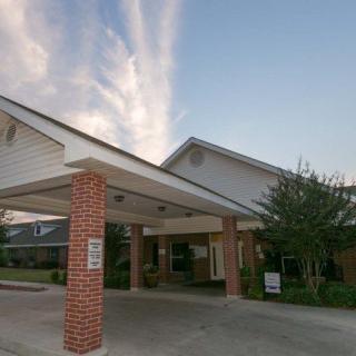 Entrance of a brick and white-paneled building with a clear sky and clouds above.