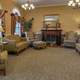 A cozy and traditionally decorated living room with a fireplace, chandeliers, and comfortable seating.