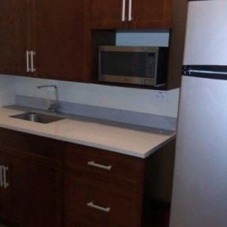 A compact kitchen area with brown cabinets, a microwave, sink, and refrigerator.