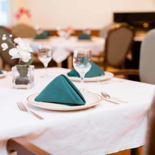 A beautifully arranged dining table with teal napkins, elegant glassware, and cutlery.