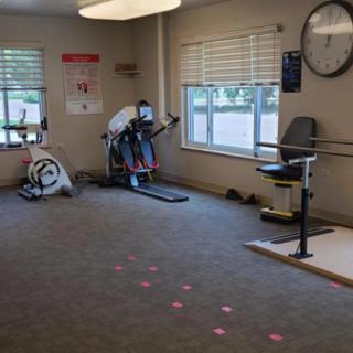 A rehabilitation area with stationary exercise bikes and parallel bars for physical therapy.