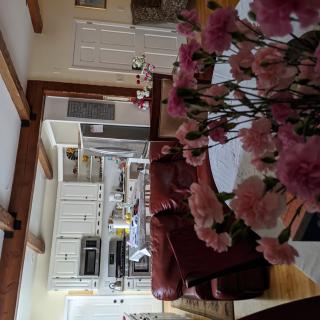 A cozy home interior featuring a kitchen and living room with pink flowers on the table.