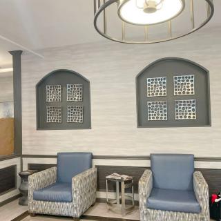 A modern lobby with two upholstered chairs and decorative wall elements.