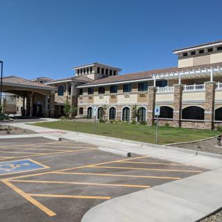 A school building with a large parking lot under a clear blue sky.