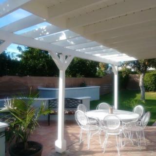 A sunny patio area with a white pergola and outdoor dining set.