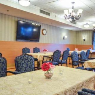 A well-furnished conference room with elegant seating, a large television, and decorative chandeliers.