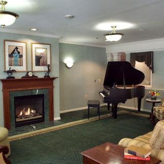 A cozy living room with a grand piano and fireplace.
