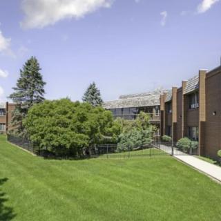 Exterior view of an apartment complex with a manicured lawn and trees.
