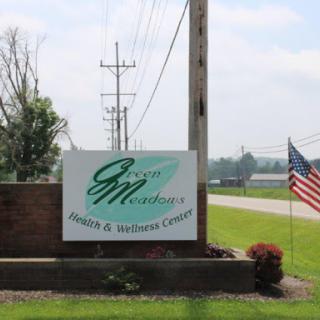 Welcome sign for a farm and seed company, featuring greenery and an American flag.