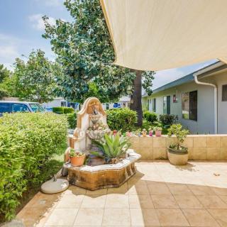 A sunny patio with a decorative fountain surrounded by lush greenery.