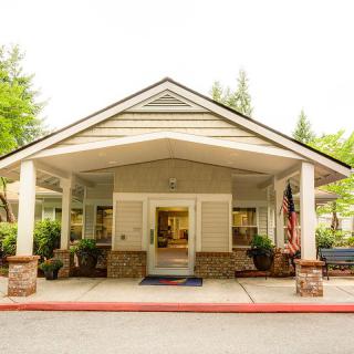 A welcoming building entrance with a covered porch surrounded by greenery.