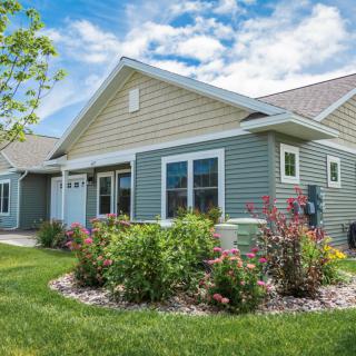 A charming suburban house with well-maintained landscaping under a blue sky.