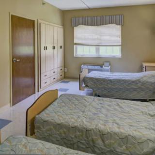 A hospital room with multiple beds and simple furnishings.