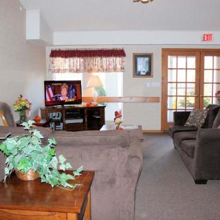 A cozy living room with a sofa, television, and decorative plants.