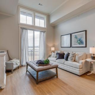 A modern living room with large windows, featuring a cozy sofa and coffee table in a neutral color palette.