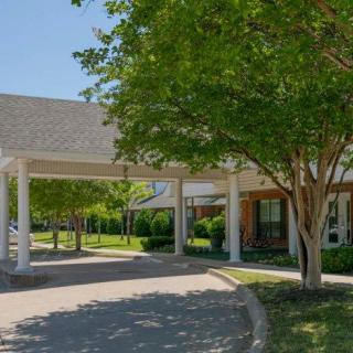 A building entrance with a covered driveway and surrounding trees.