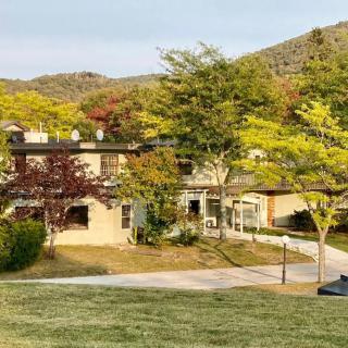 A scenic view of a house surrounded by trees and mountains.