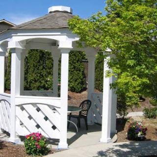 A charming white gazebo nestled in a beautiful garden, perfect for relaxation.