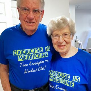 An elderly couple wearing matching blue t-shirts promoting exercise as medicine.