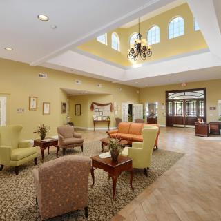 A well-lit lobby featuring a seating area with colorful furniture and a chandelier under high ceilings.