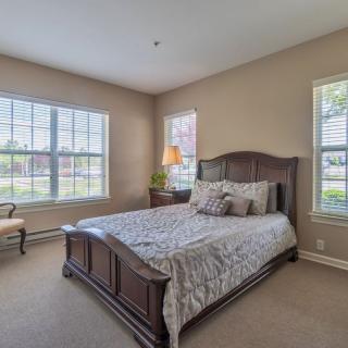 A cozy bedroom with a large bed and ample natural light from the windows.