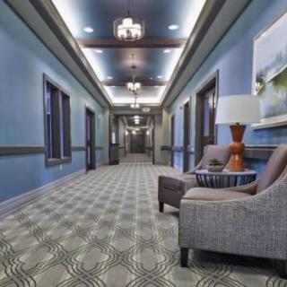 A stylish hotel hallway with patterned carpet, seating area, and elegant lighting.