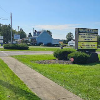A business sign stands by the roadside, surrounded by neatly trimmed grass and landscaping.