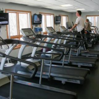 A row of treadmills in a gym with one person exercising.