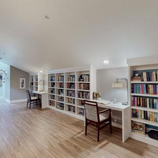 A spacious home office with built-in bookshelves, a desk, and wood flooring.