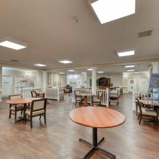 A spacious dining area featuring tables and chairs, illuminated by overhead lights.