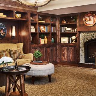 A cozy living room with wooden bookshelves, a comfortable seating area, and a fireplace.