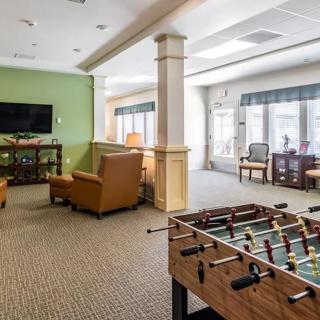 A spacious recreation room with a foosball table, comfortable seating, and a television.