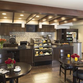 A cozy cafe interior with a seating area and a display counter filled with pastries.