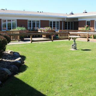 A well-maintained garden with a lawn and a building in the background.