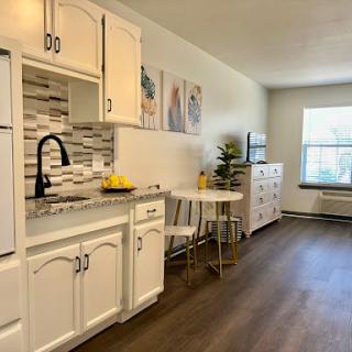 A bright and modern kitchen featuring white cabinetry, a sleek dining area, and ample natural light.