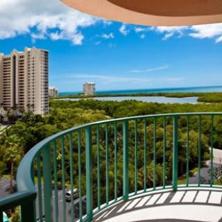 A scenic view from a balcony overlooking the cityscape, with lush greenery and bodies of water under a clear blue sky.