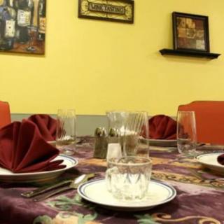 A neatly set dining table in a cozy restaurant with red napkins and glassware.