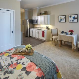 A cozy studio apartment with a bed, kitchenette, and a small dining area.