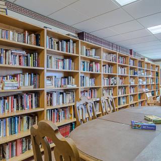 A quiet library room with rows of bookshelves and a reading table.