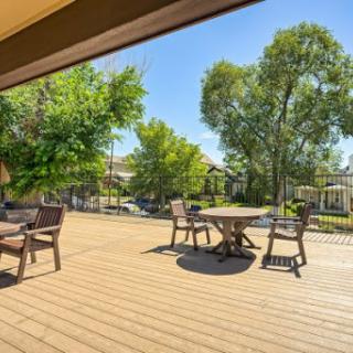 A serene outdoor deck area perfect for relaxation, surrounded by lush greenery and bathed in sunlight.