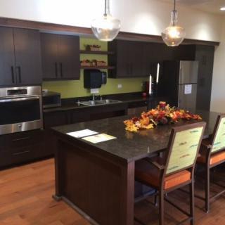 A modern kitchen with dark cabinetry, a central island with seating, and pendant lighting.
