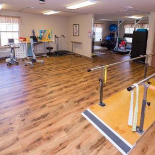 A therapy room equipped with parallel bars and various exercise equipment for rehabilitation exercises.