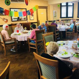 A group of elderly people enjoying a meal together in a decorated dining room.