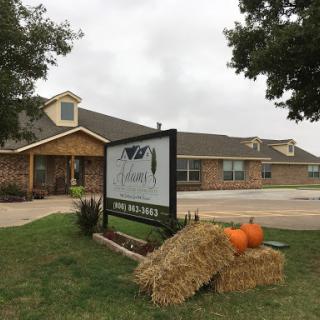 A welcoming building adorned with fall decorations, featuring pumpkins and hay bales in front of the sign.