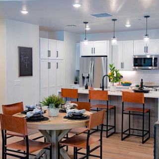 A modern kitchen and dining area featuring a sleek design with bar stools and a well-set table.
