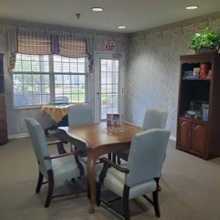 Cozy dining area with a wooden table and chairs, surrounded by windows letting in natural light.