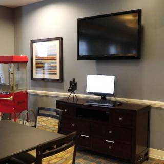 A conference room featuring a television, computer on a desk, and a popcorn machine.